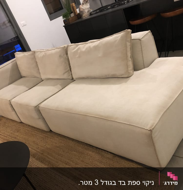 ספה בהירה עם כריות על שטיח